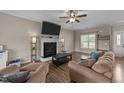Comfortable living room featuring a fireplace, ceiling fan, and wood-look flooring at 24 Kaki Ct, Selma, NC 27576