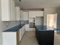 Bright kitchen featuring white cabinets, an island with a black base, and countertops with protective blue film at 3020 White Rail Dr, Fuquay Varina, NC 27526