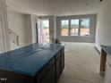 Open-concept living room with large windows, an island with a black base, and stairs with black metal railing at 3020 White Rail Dr, Fuquay Varina, NC 27526