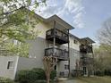 Apartment building featuring multiple private balconies, neutral-toned siding, and neatly trimmed landscaping, set amongst mature trees at 303 Smith Level Rd # E32, Chapel Hill, NC 27516