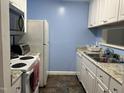Functional kitchen with white appliances, white cabinetry, and granite-look countertops, complemented by blue walls and tiled floors at 303 Smith Level Rd # E32, Chapel Hill, NC 27516