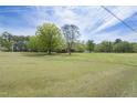 Expansive green yard showcases a well-maintained brick home beneath a cloudy sky at 3121 Blue Hill Ln, Durham, NC 27703