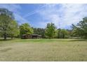 Wide view of a quaint brick home surrounded by mature shade trees in a spacious yard at 3121 Blue Hill Ln, Durham, NC 27703