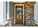 Close-up of a wood front door featuring decorative glass and stylish stonework at 353 Murray Grey Ln, Wake Forest, NC 27587