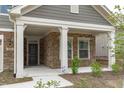 Close-up of the home's inviting front porch with stone accents, white columns, and well-maintained landscaping at 421 Raven Cliff St, Apex, NC 27523