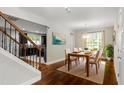 Dining room with hardwood floors, a modern chandelier, and natural light pouring in from a large window at 5417 Razan St, Raleigh, NC 27616