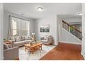 Bright living room featuring hardwood floors, a large window, and neutral-toned furniture arranged on a patterned rug at 5417 Razan St, Raleigh, NC 27616