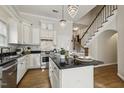Stylish kitchen featuring stainless steel appliances, granite countertops, white cabinets, an island, and hardwood floors at 604 Mills St, Raleigh, NC 27608