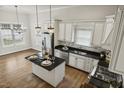 Bright kitchen boasts granite countertops, stainless appliances, white cabinetry, island with barstool seating, and hardwood flooring at 604 Mills St, Raleigh, NC 27608