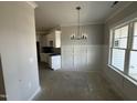 Dining room showing wainscoting details, a modern chandelier and a view into the kitchen, which has white cabinets at 69 Tee Dr, Selma, NC 27576