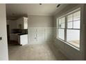 Bright, unfinished kitchen area with white cabinets, a large window and decorative wall trim at 69 Tee Dr, Selma, NC 27576