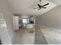 Spacious open-concept living area with a ceiling fan, connected to a kitchen with white cabinets and blue countertops at 69 Tee Dr, Selma, NC 27576