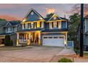 A two-story home at dusk features a covered porch, two-car garage and meticulous landscaping at 725 Ancient Oaks Dr, Holly Springs, NC 27540