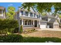 Charming two-story home features a welcoming front porch, two-car garage, and manicured lawn at 725 Ancient Oaks Dr, Holly Springs, NC 27540