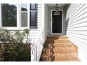 Inviting entrance to home, featuring brick steps, white railing, and black door at 901 Clifford Dr, Durham, NC 27704