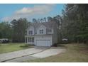Traditional two-story home with a two-car garage, light siding, blue shutters and mature trees at 910 Cedar Creek Dr, Wendell, NC 27591