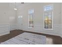 Bright living room featuring dark floors, wainscoting, and two large windows offering plenty of natural light at 10410 Sablewood Dr # 111, Raleigh, NC 27617