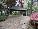 Large brick carport offers ample space and is surrounded by lush greenery and beautiful flowers at 106 Orchard Rd, Henderson, NC 27536