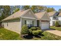 Single-story home showcasing its charming exterior, lush landscaping and a convenient two-car garage at 112 Pink Dogwood Ln, Mebane, NC 27302