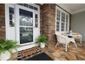 Inviting front porch with stone flooring and white wicker furniture, perfect for relaxing at 1120 Scholastic Cir, Durham, NC 27713