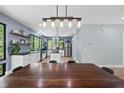 Open dining and kitchen area with modern lighting fixtures, stainless steel appliances, and large windows with a wooded view at 1401 Freshwater Ct, Wake Forest, NC 27587