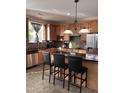 Well-lit kitchen with granite countertops, stainless steel appliances, island with bar stools, and warm wooden cabinetry at 141 Steel Hopper Way, Garner, NC 27529