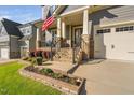 Home exterior features a covered porch, stone accents, a manicured lawn, and a two-car garage at 212 Blue Granite Dr, Holly Springs, NC 27540