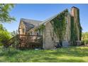 Exterior view of the back of the house featuring a chimney with vines and a wooden deck at 2510 Poplar Creek Rd, Henderson, NC 27537