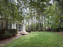 Spacious backyard with lush greenery, a brick patio, and mature trees providing shade at 3300 Magical Pl, Raleigh, NC 27614