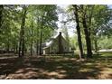 Back exterior of home with brick chimney and fenced-in yard surrounded by mature trees at 5200 Lorbacher Rd, Apex, NC 27539