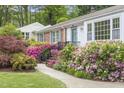 Inviting single story home featuring a brick accent, complemented by vibrant azaleas and lush greenery at 611 Beaver Dam Rd, Raleigh, NC 27607