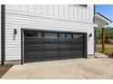 Modern black garage door with windows and concrete driveway of a white two-story home at 836 Day Ave, Burlington, NC 27217