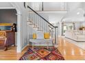 Inviting foyer with staircase, colorful rug, bench seating and hardwood floors at 8409 Muirfield Dr, Fuquay Varina, NC 27526