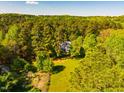 Aerial shot of a charming white house surrounded by lush trees on a large lot, offering privacy and tranquility at 910 Old Orchard Rd, Chapel Hill, NC 27517