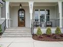 Inviting front porch with stone steps, seating, and elegant wooden door, perfect for relaxing at 921 Lily Claire Ln, Fuquay Varina, NC 27526