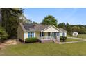 Bright yellow home with solar panels features a quaint front porch, blue shutters, and a large, open yard with green grass at 10 Gray Bass Ct, Zebulon, NC 27597