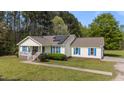 Inviting single-story home with a charming front porch, solar panels, blue shutters, and a well-maintained front lawn at 10 Gray Bass Ct, Zebulon, NC 27597