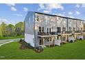 Back exterior view of townhomes with a grassy backyard and a private balcony with black metal railings at 10516 Pleasant Branch Dr # 34, Raleigh, NC 27614