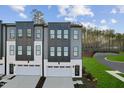 Eye-level view of modern townhomes with gray and white exteriors, each with a garage and driveway at 10516 Pleasant Branch Dr # 34, Raleigh, NC 27614