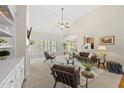 Bright, open living room with a vaulted ceiling, fan, and large windows bringing in natural light at 129 Camille Cir, Youngsville, NC 27596