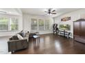 Cozy living room with large windows, hardwood floors, a comfortable sofa, and a television for entertainment at 204 Concordia Woods Dr, Morrisville, NC 27560