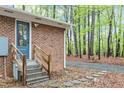 Side entrance with stone steps, wooden handrail, and glass panel door at 2314 Clements Dr, Durham, NC 27704