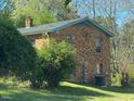 View of the rear of a brick home showing the roof, gutters and an air conditioning unit at 24 Pine St, Franklinton, NC 27525