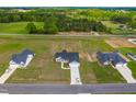 Aerial view showcasing the community featuring well-maintained homes, green lawns, and lush trees at 241 Indigo St, Lillington, NC 27546