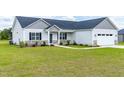 Single-Gathering home with gray siding, manicured lawn, stone accents, and a two-car garage at 241 Indigo St, Lillington, NC 27546