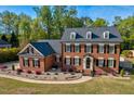 Elegant brick home featuring a well-maintained lawn and landscaping with a circular driveway and mature trees at 3001 Greystone Dr, Rocky Mount, NC 27804