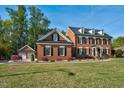 Traditional brick home featuring a manicured lawn and three-car garage surrounded by beautiful greenery at 3001 Greystone Dr, Rocky Mount, NC 27804