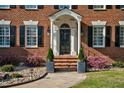 Charming front entrance with a classic black door, brick steps, stone landscaping, and lush greenery at 3001 Greystone Dr, Rocky Mount, NC 27804