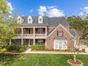 Charming brick home with a double front porch, dormer windows, and a lush green lawn at 312 Alliance Cir, Cary, NC 27519