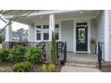 Inviting front porch with black metal railing, wicker chairs and a decorative wreath on the front door at 408 Torwood Cir, Apex, NC 27523